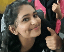 a young woman is giving a thumbs up sign