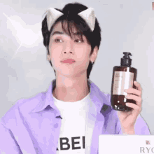 a young man wearing cat ears holds up a bottle of lotion