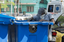 a man standing in front of a blue bin that says ambulance on it