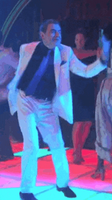 a man in a suit and tie is dancing on a neon dance floor .