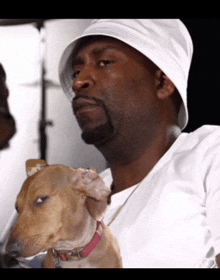 a man in a white hat holds a brown dog