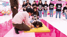 a man is kneeling down next to a woman on a mat while a group of girls stand behind him .