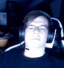 a young man wearing headphones and glasses is sitting in a chair .