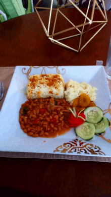 a plate of food with beans mashed potatoes and cucumbers on a wooden table