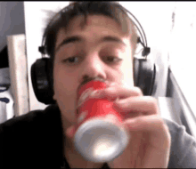 a man wearing headphones is drinking from a can