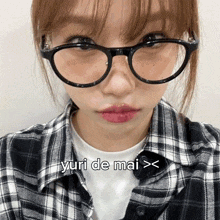 a girl wearing glasses and a plaid shirt has yuri de mai written on her face