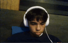 a young man wearing white headphones is laying down on a couch