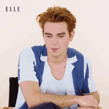 a man with red hair is wearing a blue and white shirt with the word elle on the bottom right