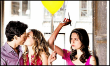 a man kissing two women while a woman holds a yellow balloon