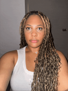 a woman with dreadlocks and a white tank top