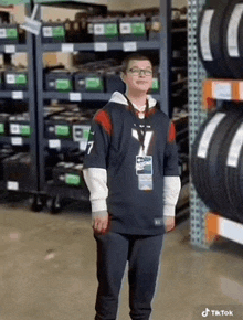 a man wearing a jersey with the number 7 on it stands in front of a stack of tires .