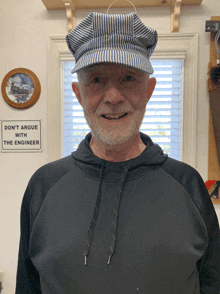 a man wearing a striped hat stands in front of a sign that says " don 't argue with the engineer "