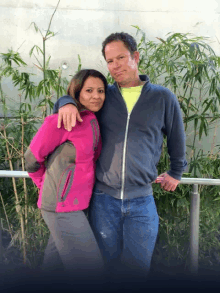 a man and a woman posing for a picture with the woman wearing a pink jacket that says adidas