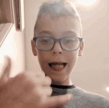 a young boy wearing glasses is giving a thumbs up sign