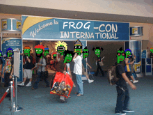 a group of people are gathered under a sign that says welcome to frog con international