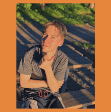 a young man sitting at a picnic table with his arm crossed