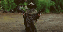 a man in a hooded cape is holding two guns in his hands