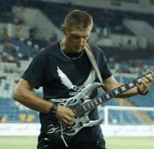 a man playing a guitar in a stadium with a shirt that says guns on it