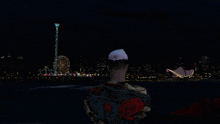 a man with a flower in his hair is looking at a ferris wheel at night