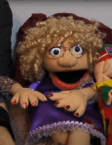 a puppet with curly blonde hair and red nails