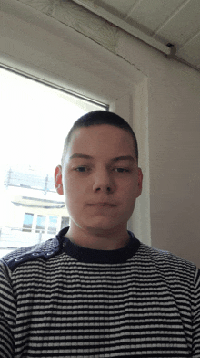 a young man wearing a black and white striped sweater looks at the camera