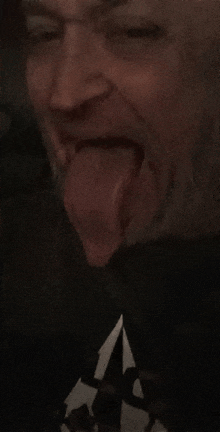 a man with a beard is sticking his tongue out in a dark room .