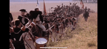 a large group of soldiers are marching through a grassy field .