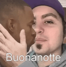 a man in a purple hat kisses another man on the cheek with the words buonanotte written below him