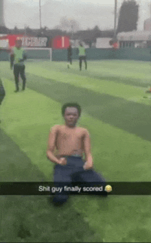 a shirtless man is kneeling down on a soccer field with the words shit guy finally scored