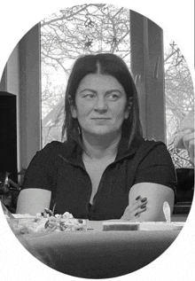 a woman in a black shirt sits at a table with food