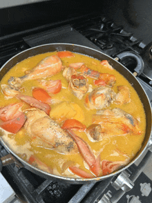 a pan filled with chicken and tomatoes on a stove top