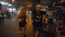 a man and a woman are dancing on a street and the man is wearing a shirt that says corse