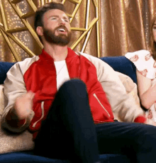 a man in a red and white jacket is sitting on a couch