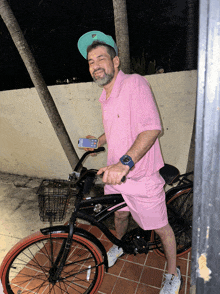 a man in a pink polo shirt is riding a bicycle