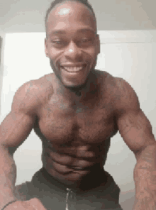 a shirtless man with a tattoo on his chest smiles for the camera