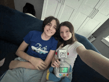 a boy and a girl are sitting on a couch with a robot toy