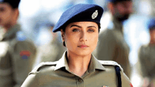 a woman in a police uniform and beret is standing in front of a group of men .