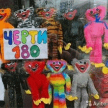 a bunch of stuffed animals are standing next to each other in front of a sign .