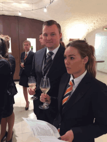 a man in a suit and tie holds a glass of wine