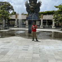 a man standing in front of a fountain wearing a red shirt that says ' samurai '