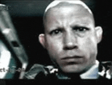 a close up of a bald man 's face with a serious look on his face .