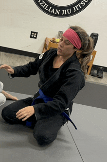 a woman kneeling on a mat in front of a brazilian jiu jitsu logo