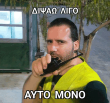 a man wearing a yellow vest is holding a walkie talkie in his mouth and the words ayto mono are below him