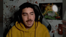 a man in a yellow hoodie is wearing headphones while sitting in a chair