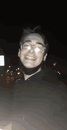 a young man wearing glasses and a black mask is smiling at the camera