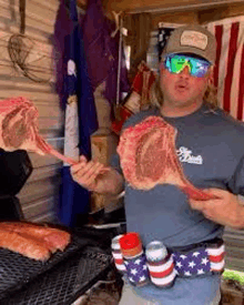 a man wearing sunglasses and a hat is holding a piece of meat .