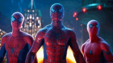 three spider-man are standing next to each other in front of a city .