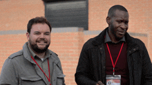 two men standing next to each other with one wearing a lanyard with a name tag that says ' chris '