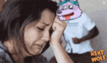 a woman is crying in front of a picture of a cartoon wolf .