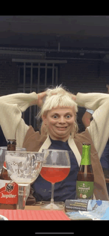 a woman sitting at a table with a bottle of jupiler beer in front of her